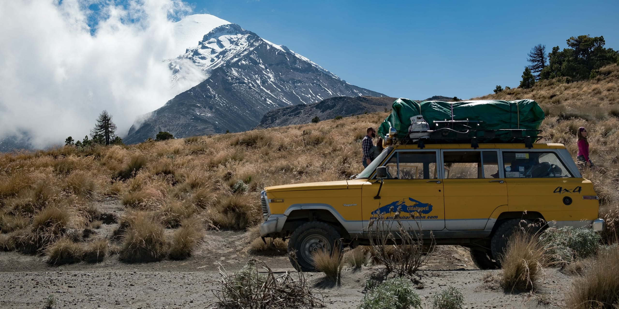 Yellow Jeep Wagoneer below a mountain: Auto Glass Glossary, Blue Chip Auto Glass