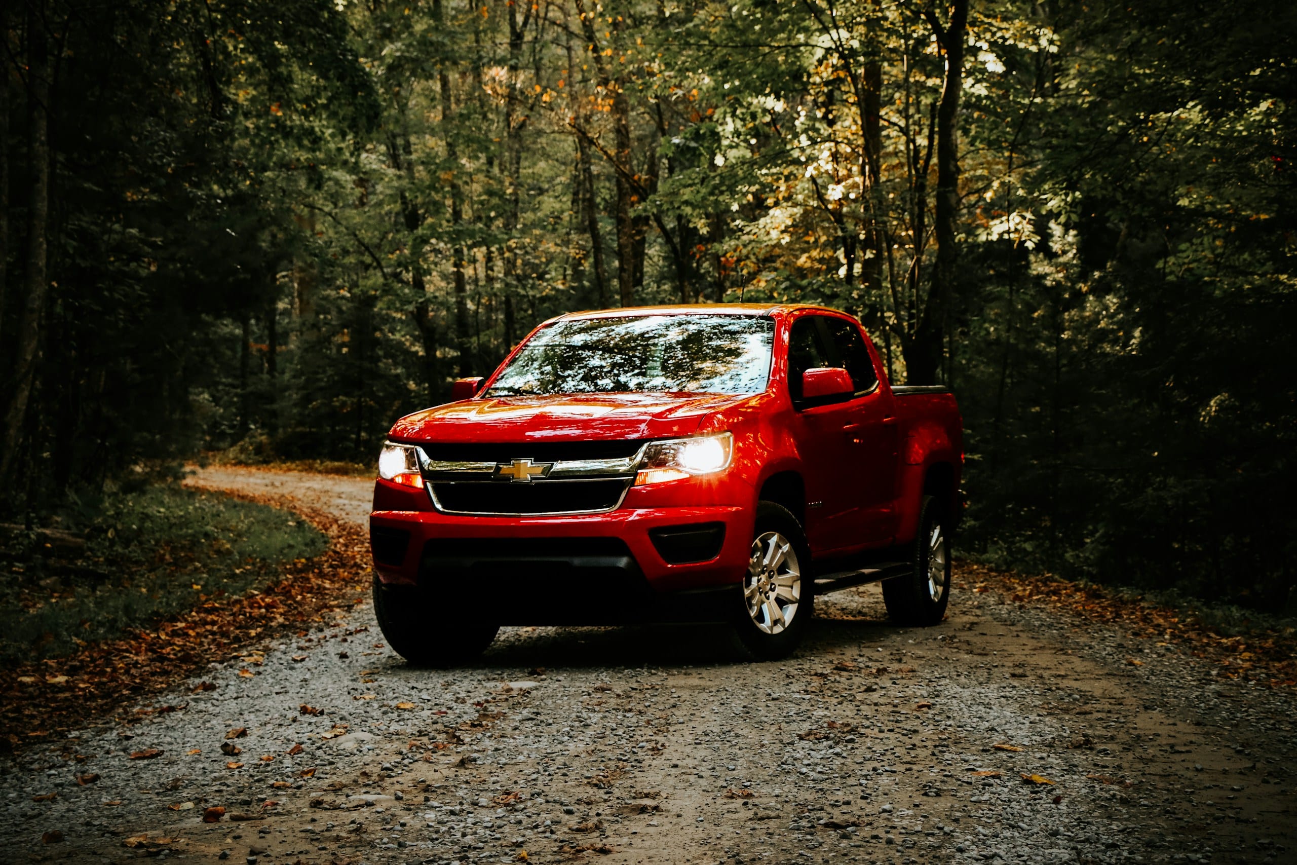 Red Chevrolet Colorado on a dirt road: Chevrolet Windshield Replacement, Blue Chip Auto Glass