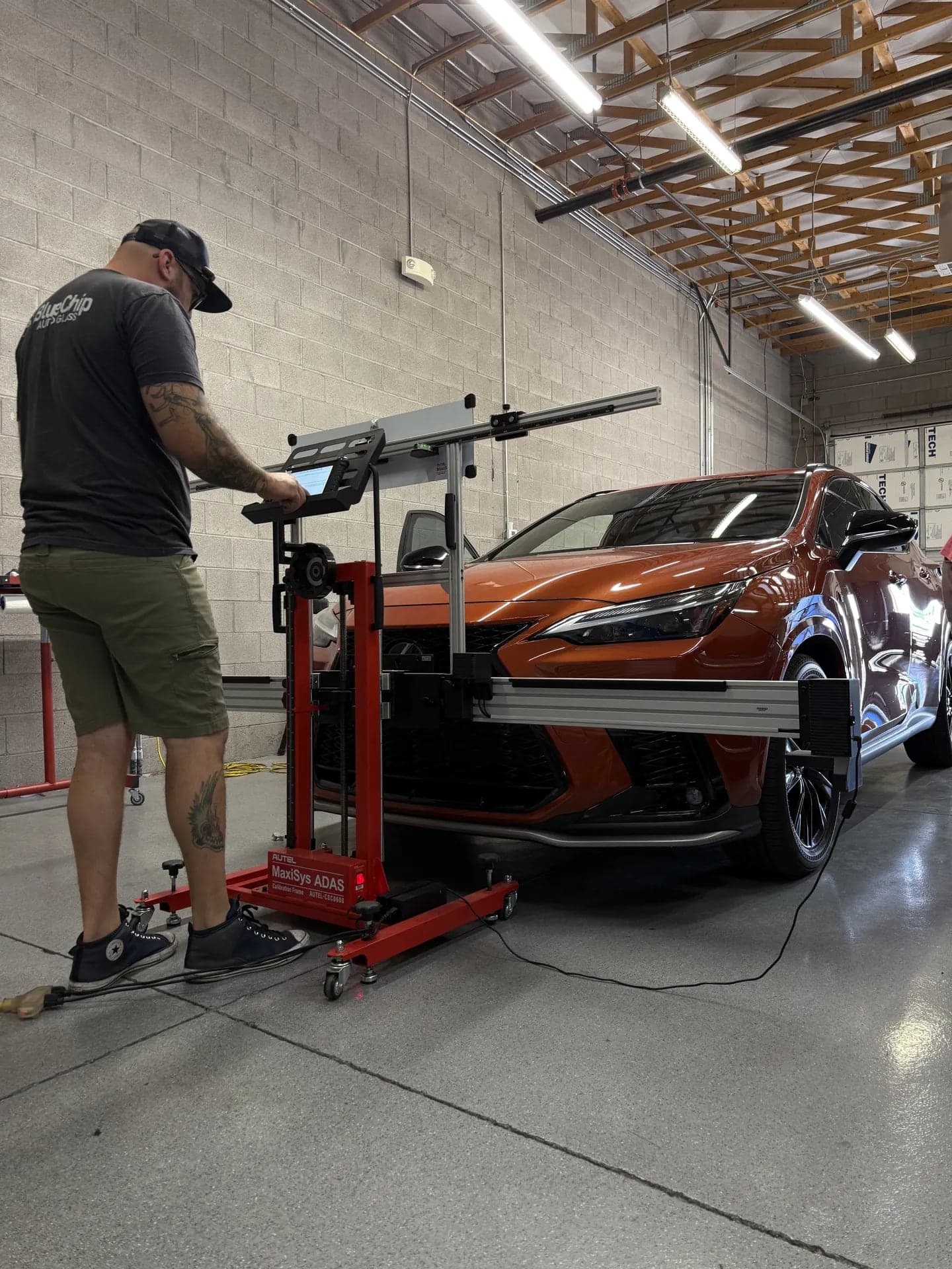 Blue Chip technician at the Autel MaxiSys ADAS calibration frame in front of an orange Lexus