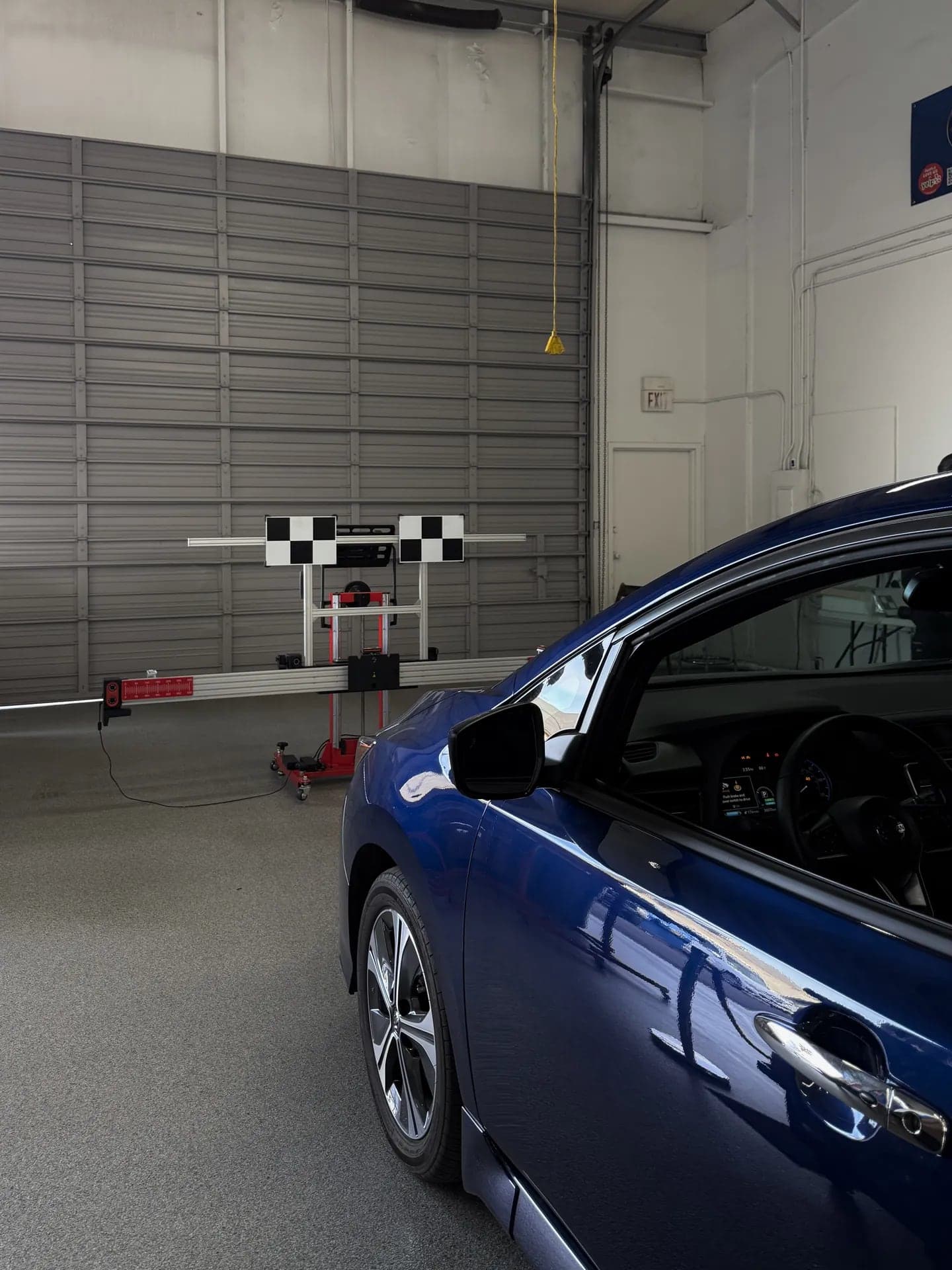 Blue Nissan facing the Autel calibration stand and targets