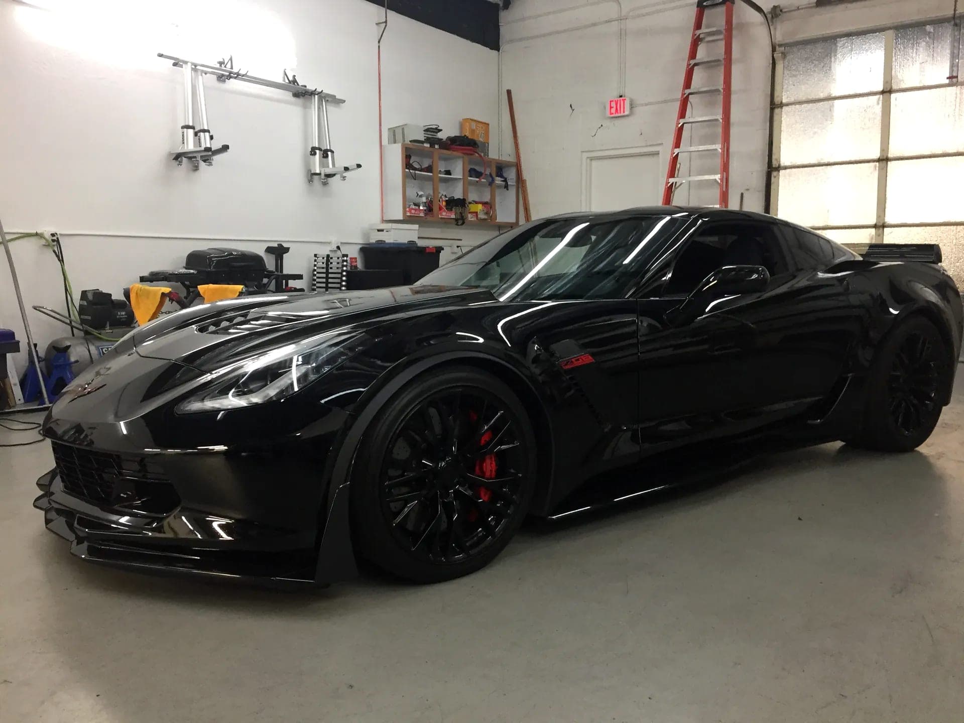 Blue Chip Auto Glass technician installing glass on a black Corvette Z06