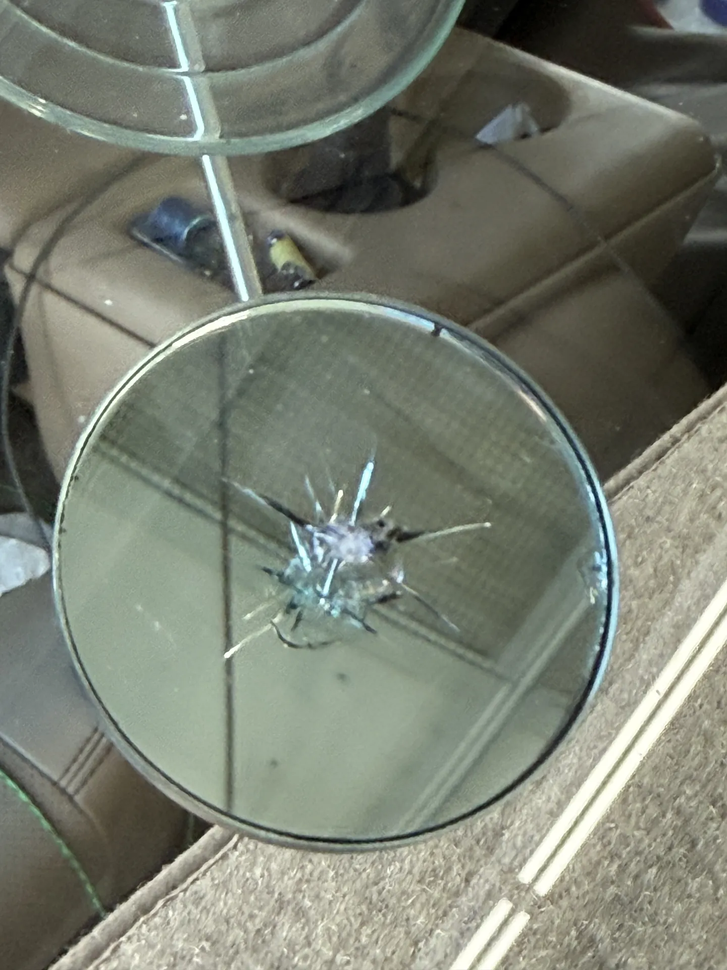 Star-shaped rock chip in a windshield, inspected before repair