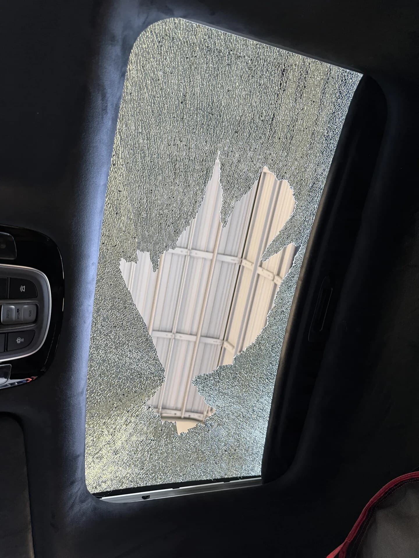 Shattered sunroof glass still hanging in the frame, seen from inside the car