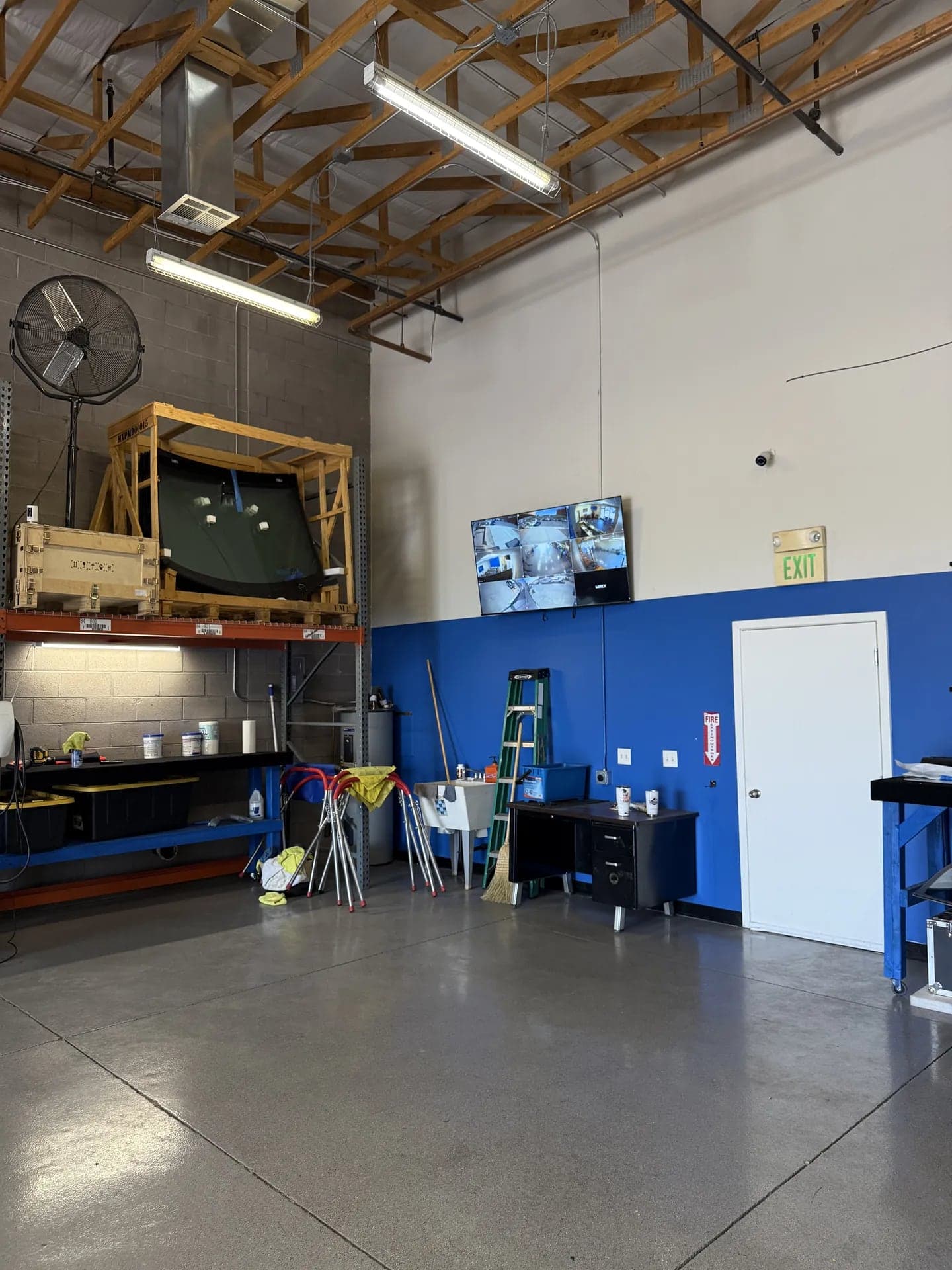 Mesa shop service bay with a crated windshield on the rack and the blue Blue Chip wall