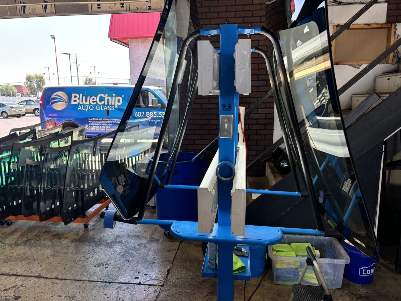 Glass delivery cart loaded with windshields next to a Blue Chip van