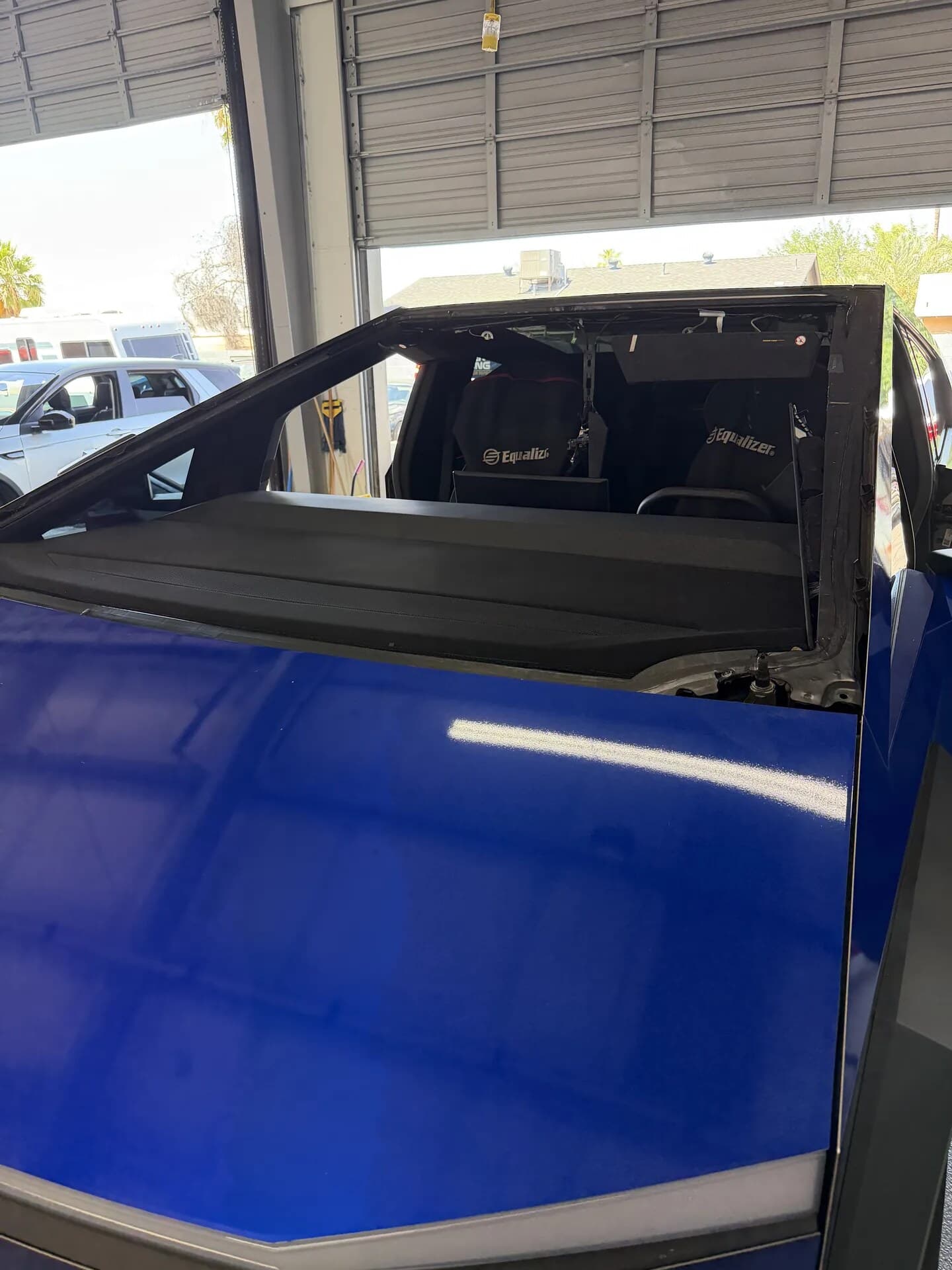 Blue Tesla Cybertruck with the windshield removed in the Blue Chip Auto Glass shop