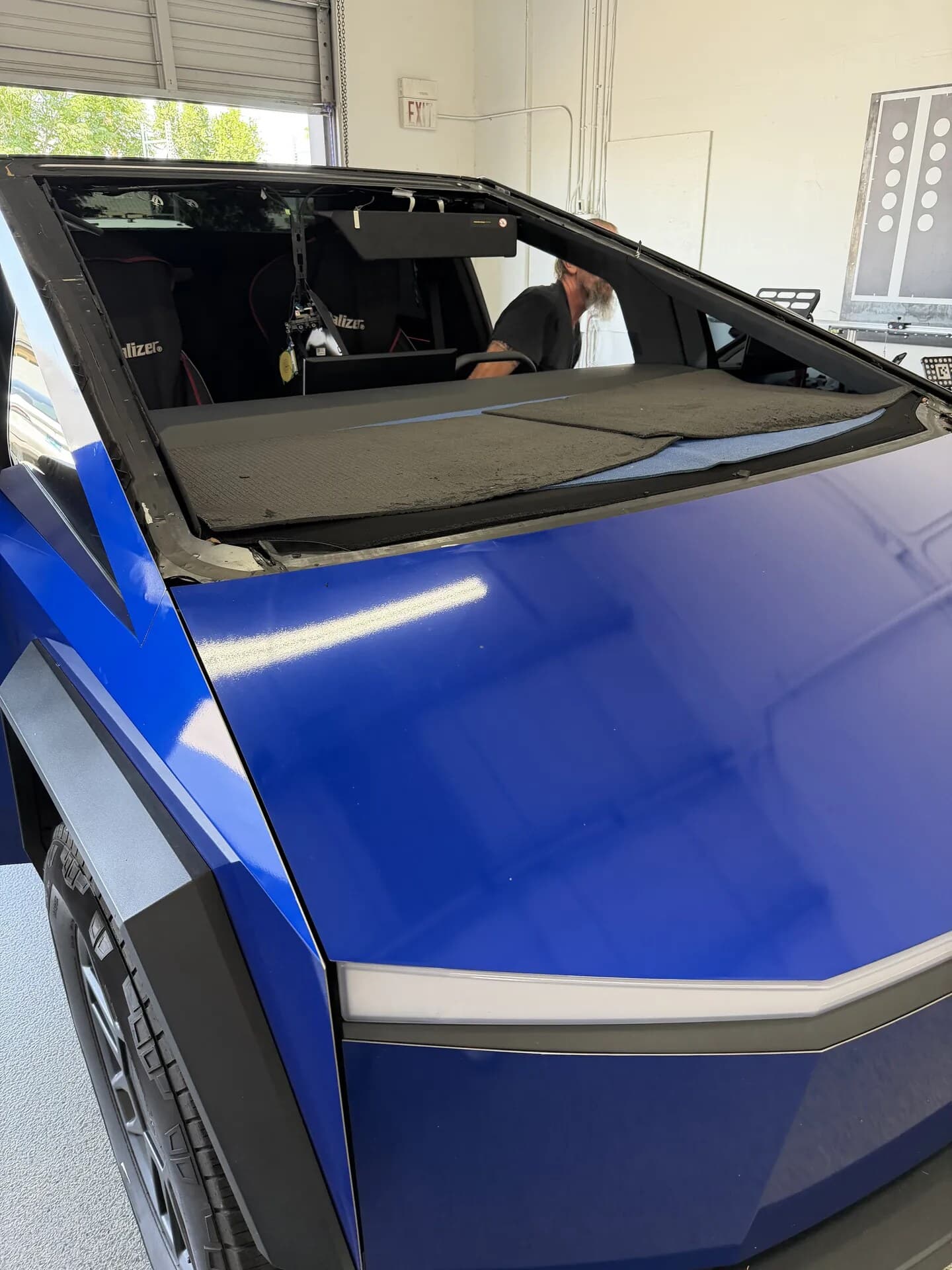 Blue Chip technician inside a blue Tesla Cybertruck with the windshield opening covered