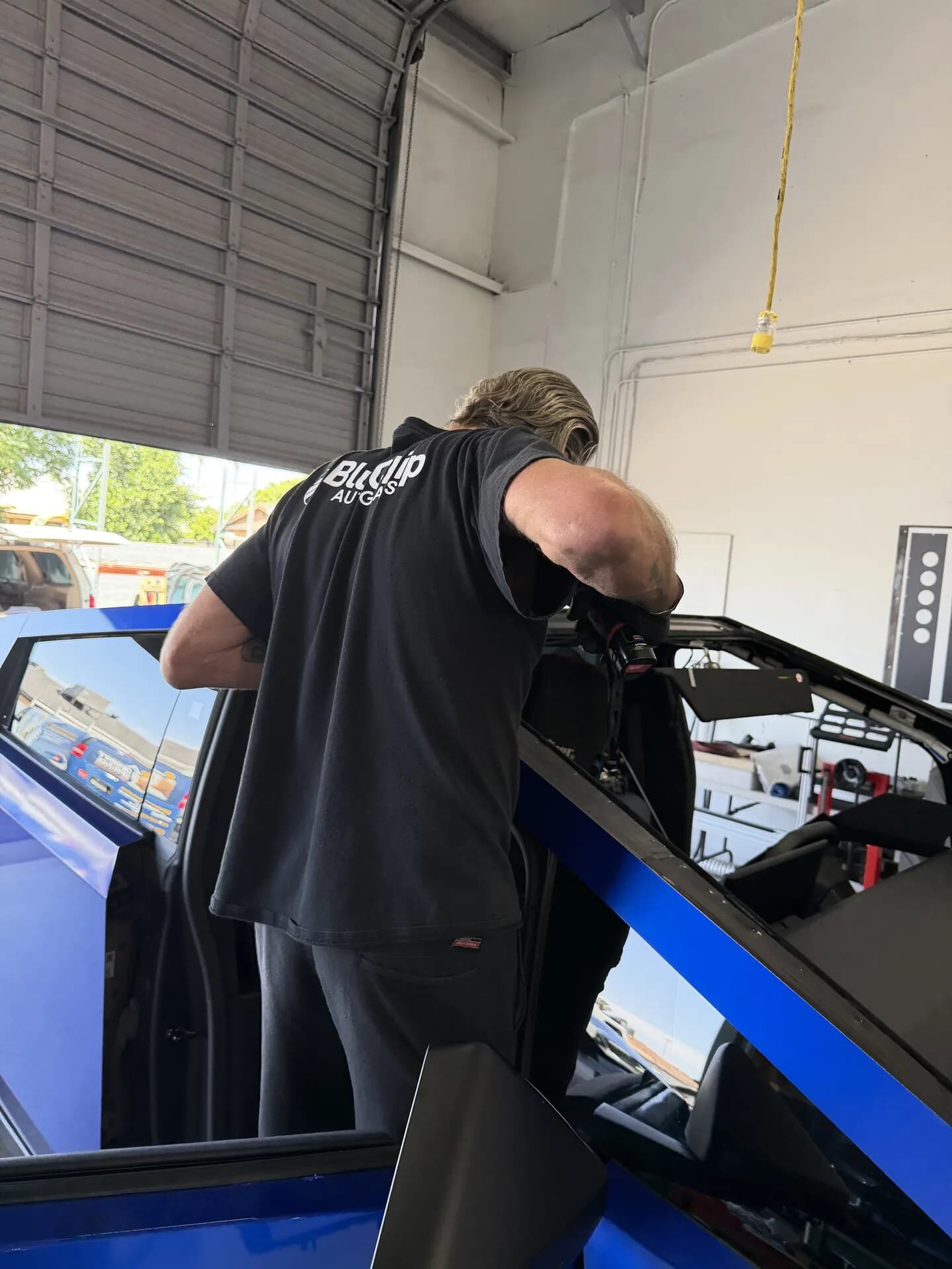 Blue Chip technician working at the open door of a blue Tesla Cybertruck