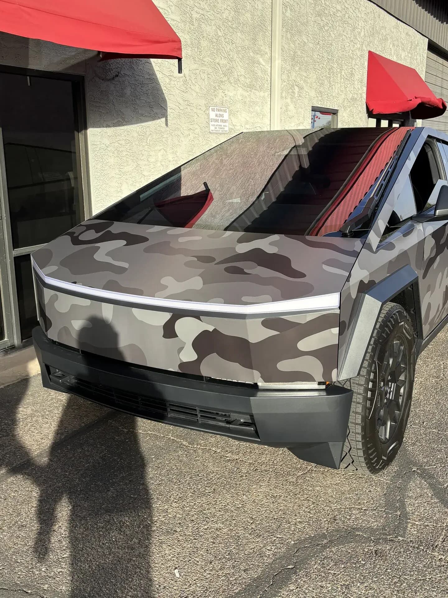 Front of a camo-wrapped Tesla Cybertruck with its new windshield