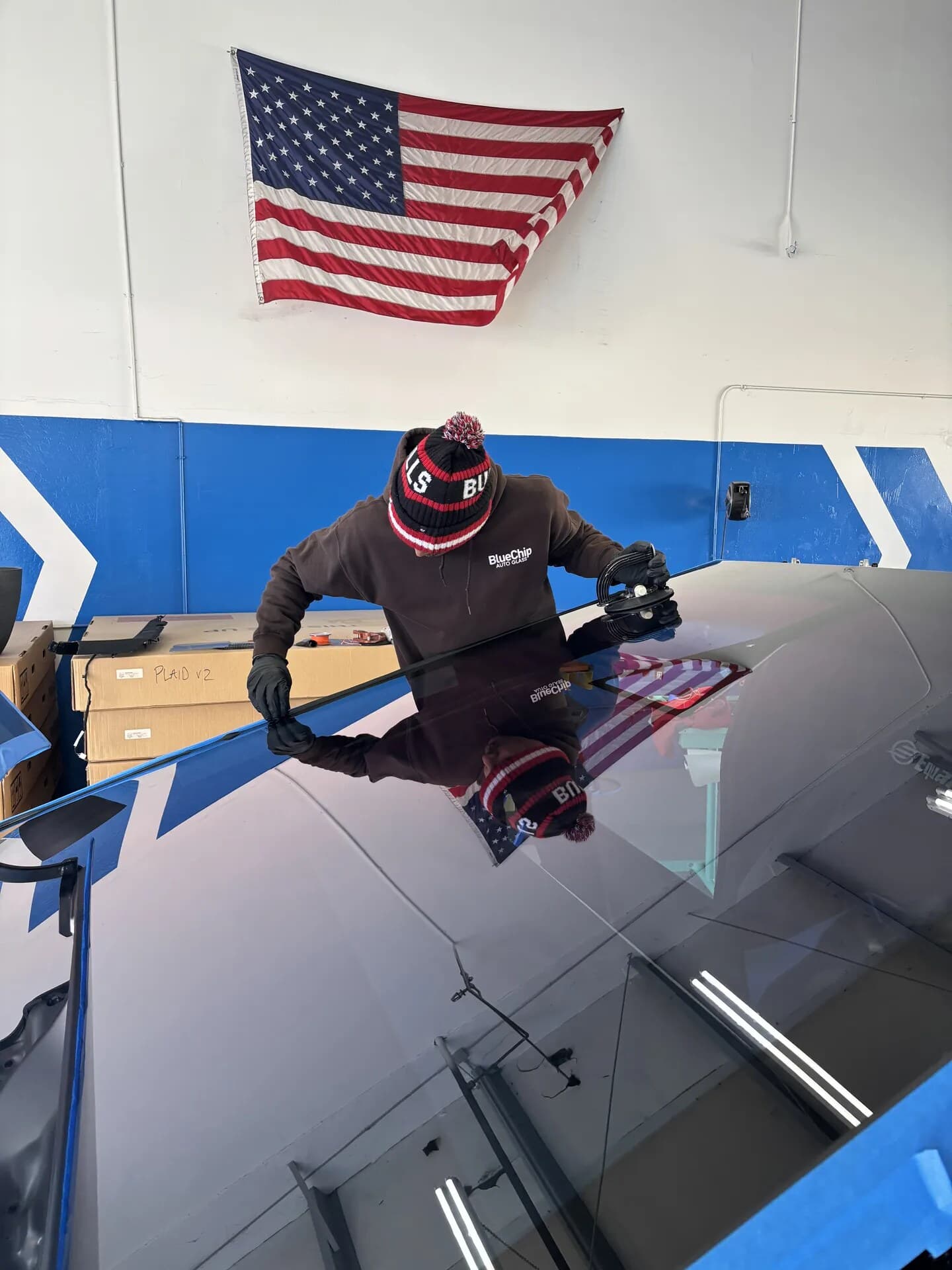 Blue Chip technician setting Tesla glass with suction cups in the shop