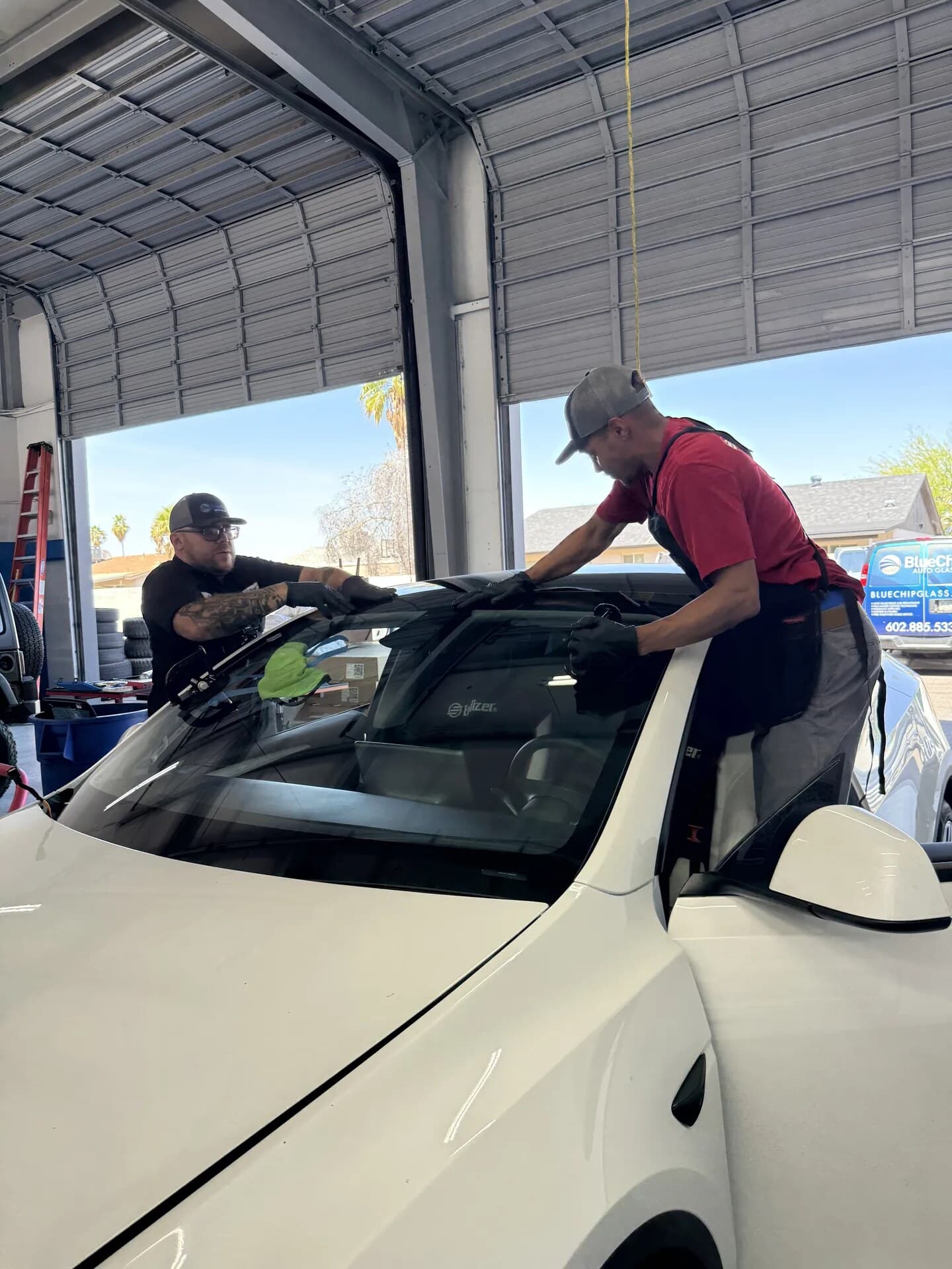 Blue Chip technicians lining up a new Tesla Model 3 windshield in the shop