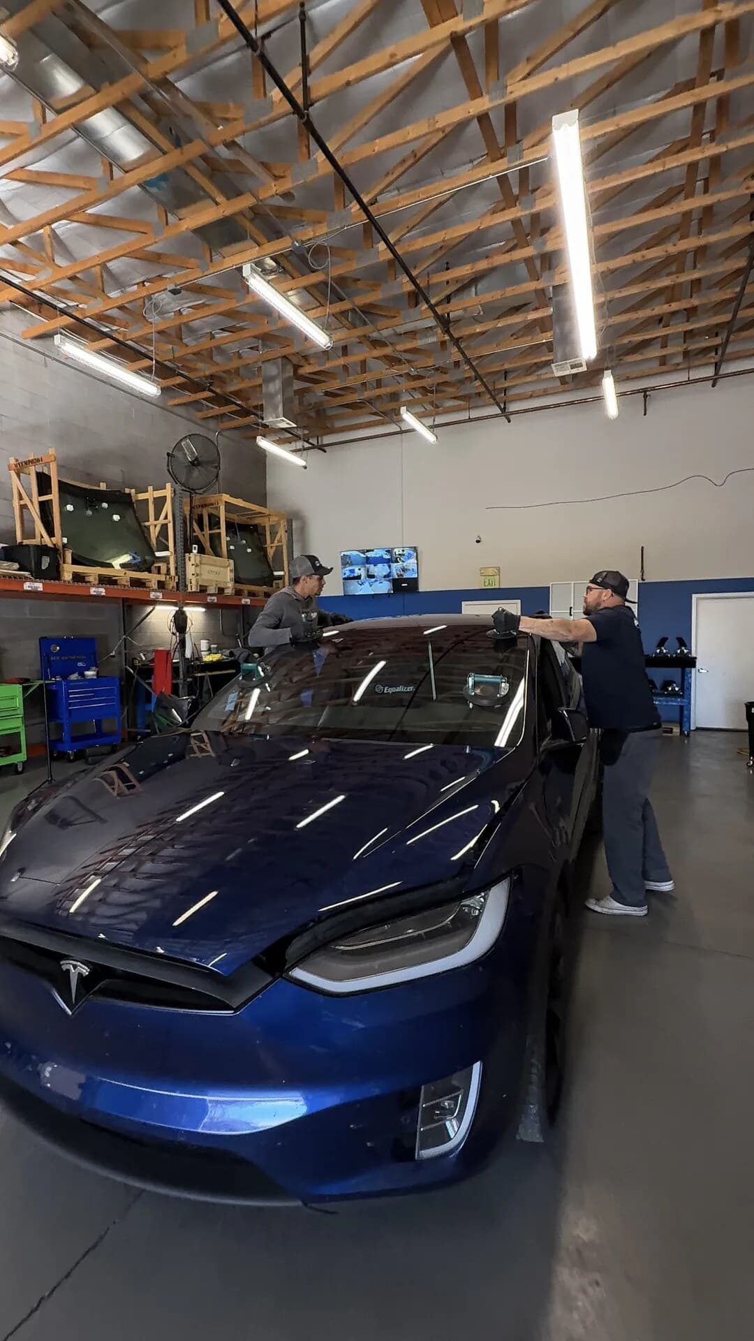 Two Blue Chip technicians setting a new windshield on a blue Tesla Model X