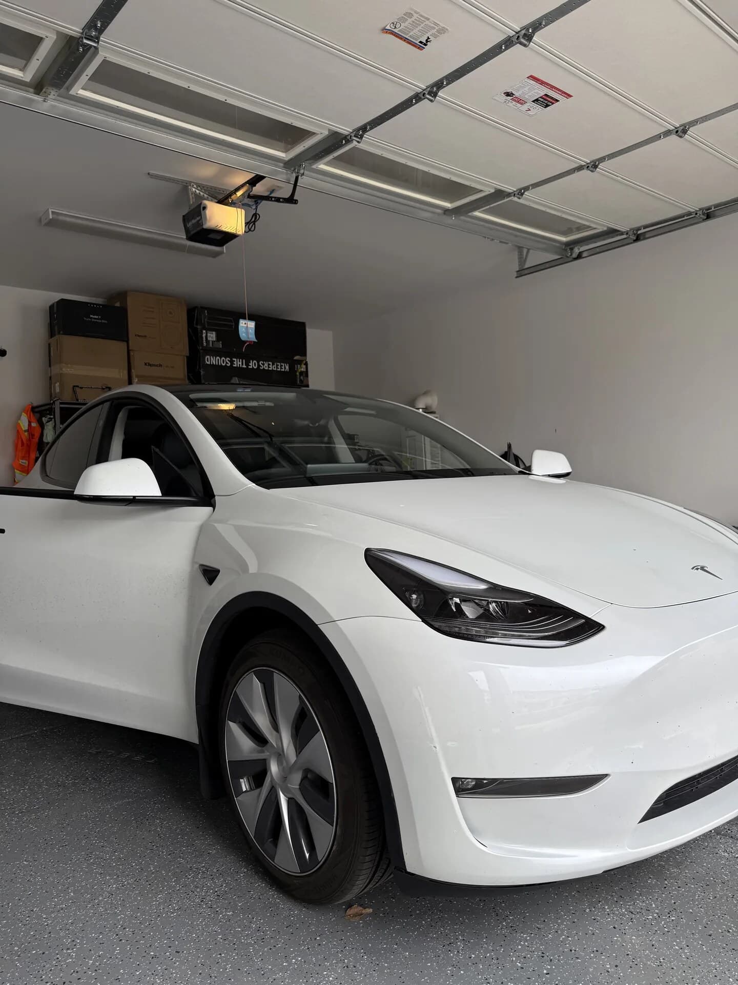 White Tesla Model Y with a new windshield in a customer's garage after a Blue Chip mobile replacement