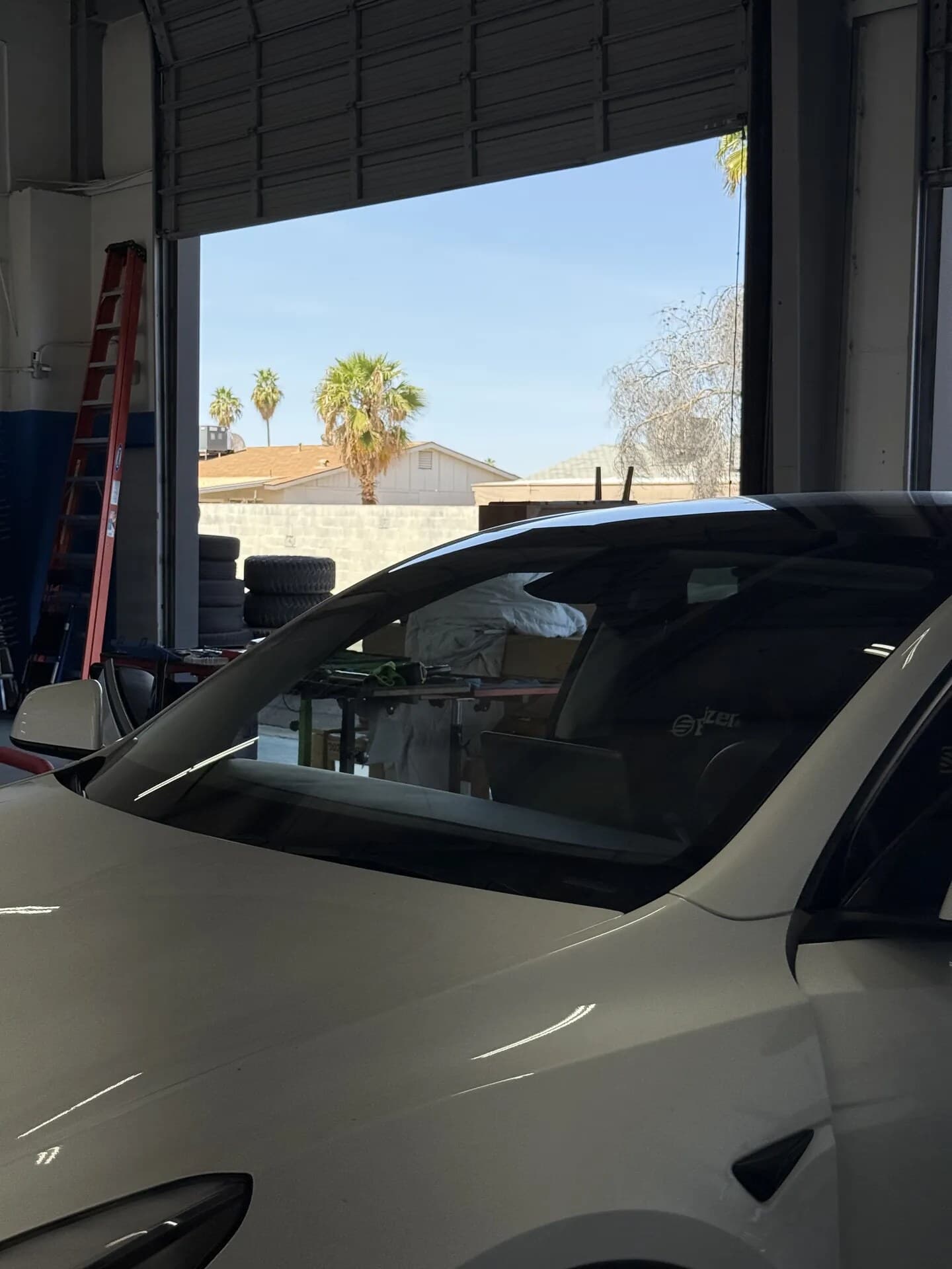 Close-up of a new windshield on a white Tesla Model Y in the Blue Chip Auto Glass shop