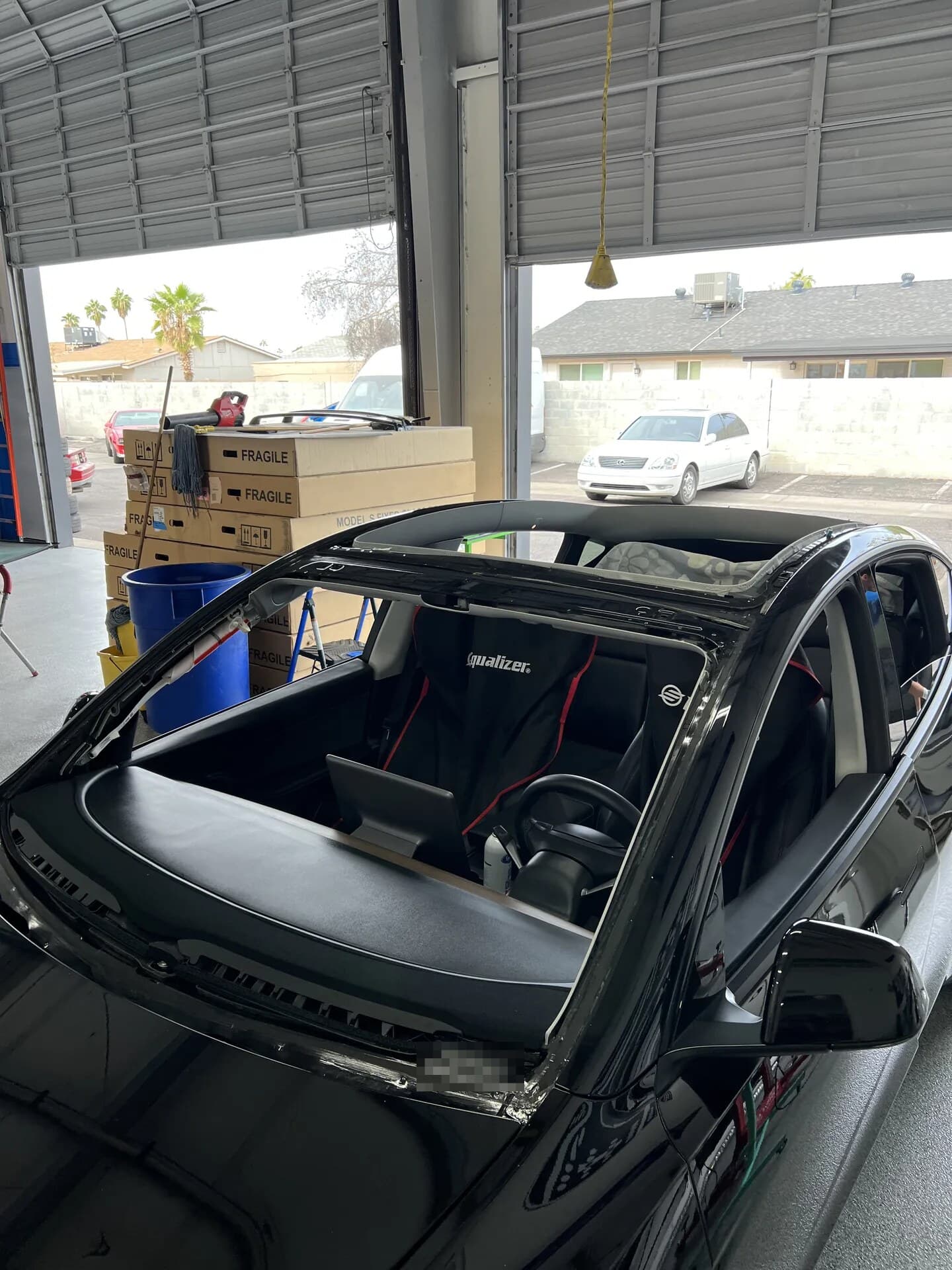 Black Tesla Model Y with the windshield and glass roof both removed in the Blue Chip shop