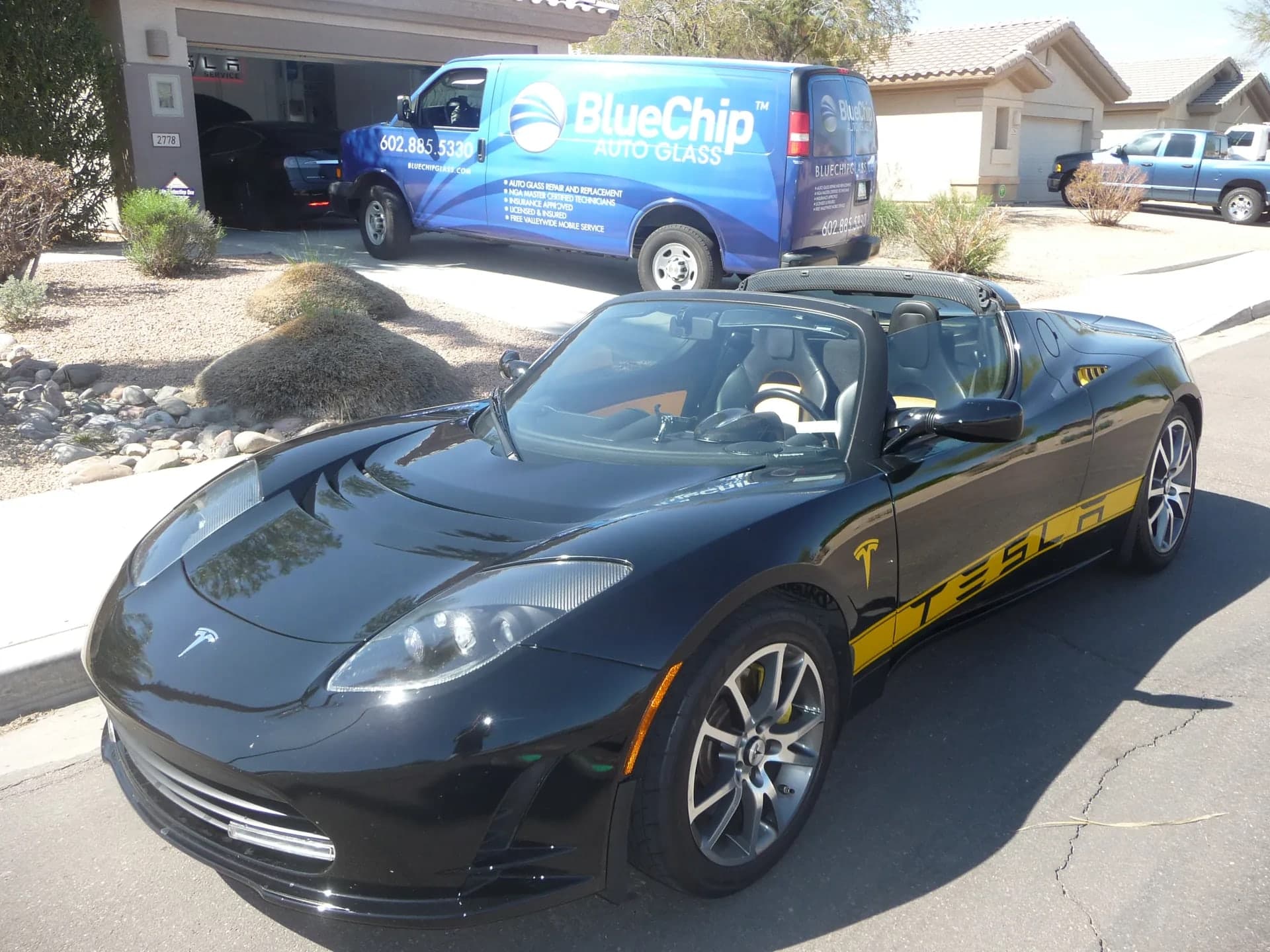Tesla Roadster in a customer's driveway with the Blue Chip Auto Glass van behind it
